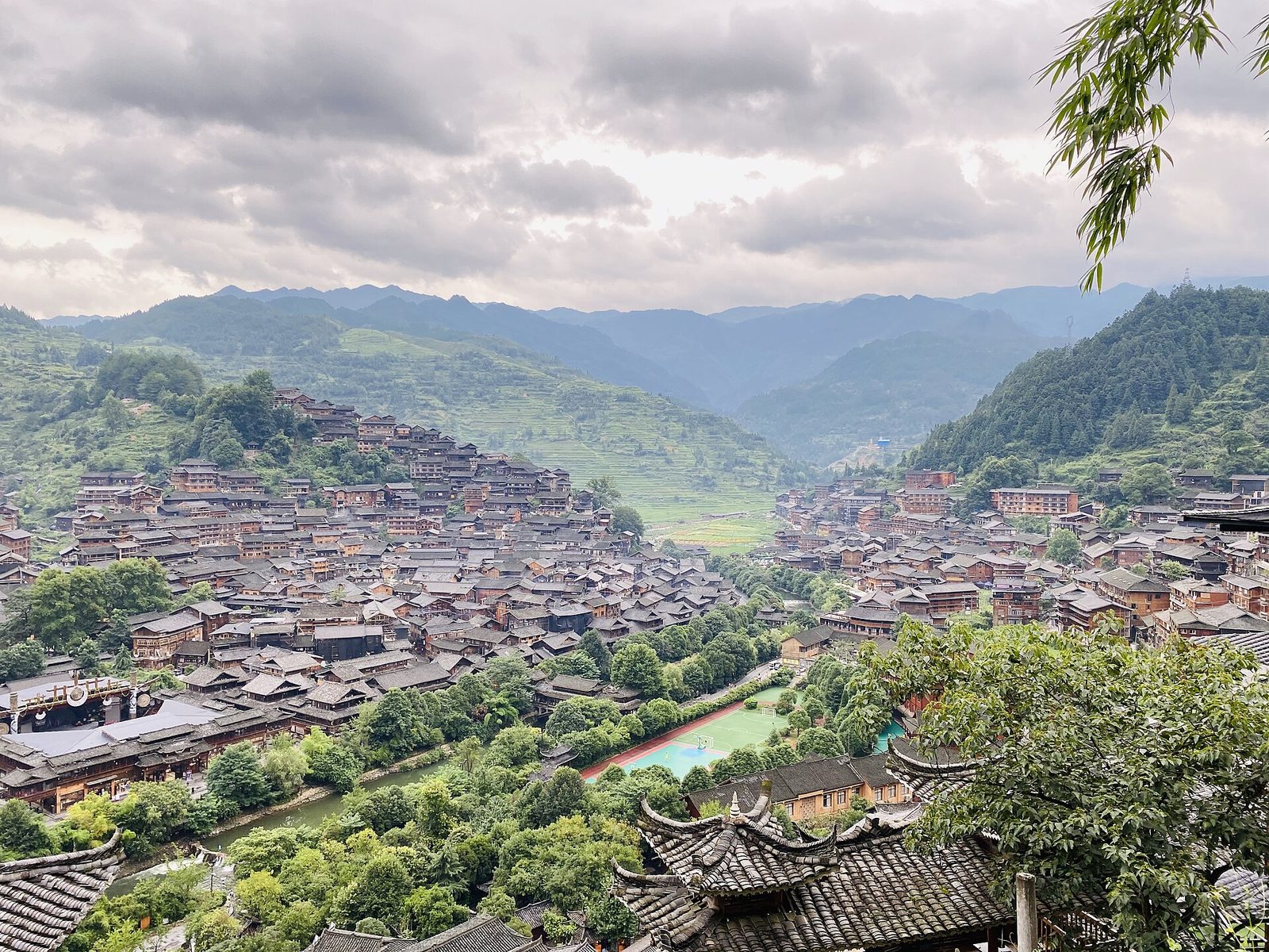 Stilt houses of a Miao village spread across a green valley in Guizhou
